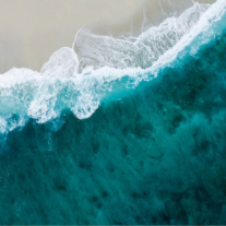 Turquoise waves washing up on a tan beach. 