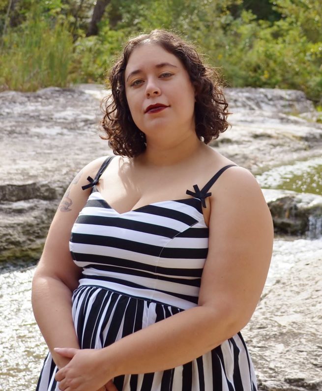 Leticia is outside wearing a white and black striped dress.