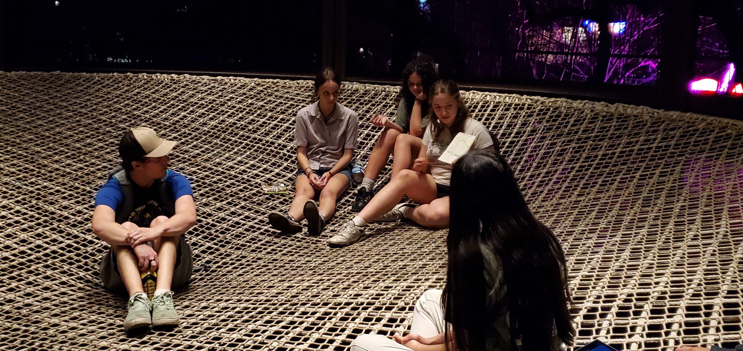 Students from Austin Youth River Watch share their advocacy zines with each other in the net hammock at Pease Park